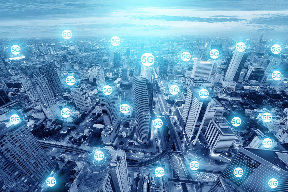 Cityscape view overlaid with multiple glowing "5G" icons, illustrating the widespread availability of next-generation mobile network coverage in an urban environment.